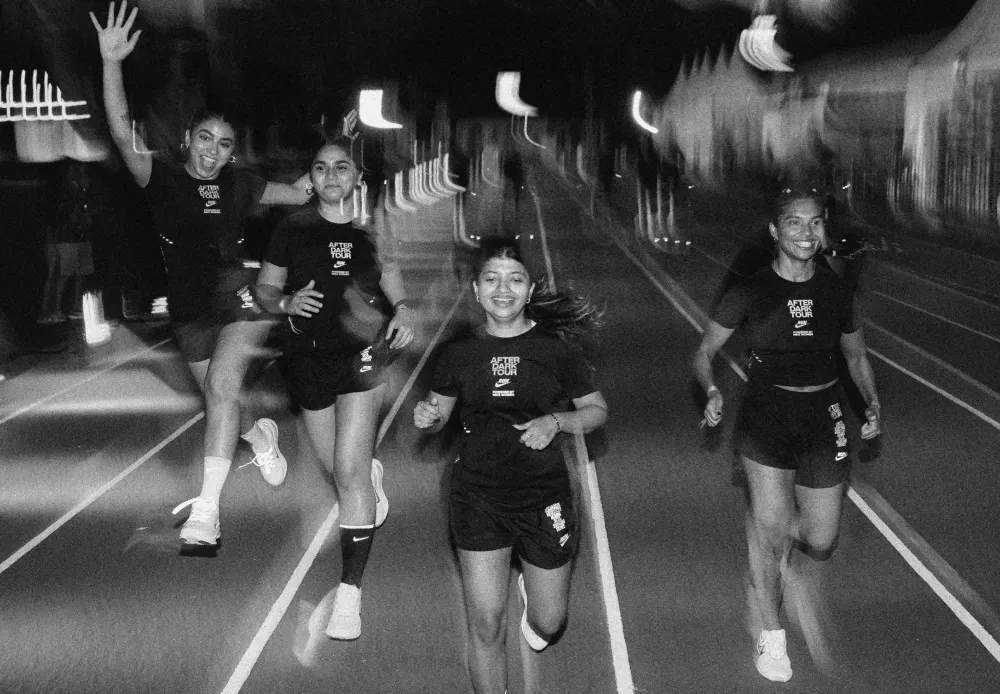 Runners in After Dark Tour tees running toward the camera on a floodlit night street