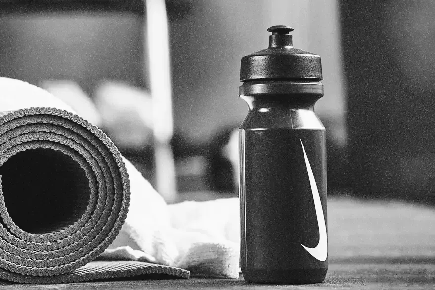 A Nike water bottle beside a rolled yoga mat and towel