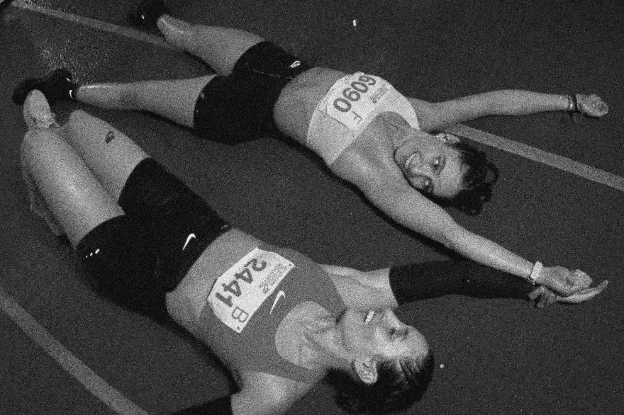 Two runners lying on the ground stretching after a race