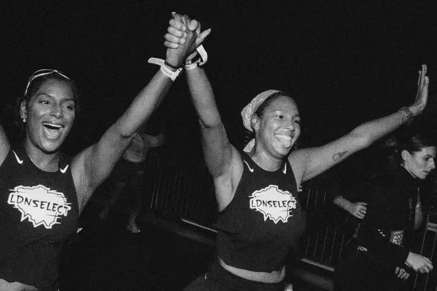 Two runners celebrating with raised joined hands after a night run