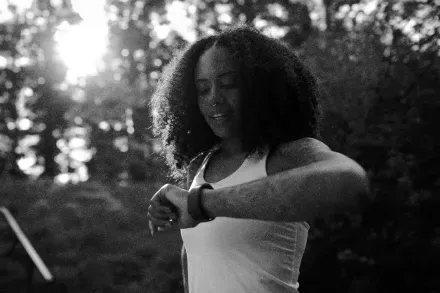 A runner checking her watch in a forest