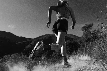A runner on a dusty hillside trail