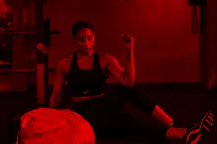 A woman resting on a mat in a red-lit gym